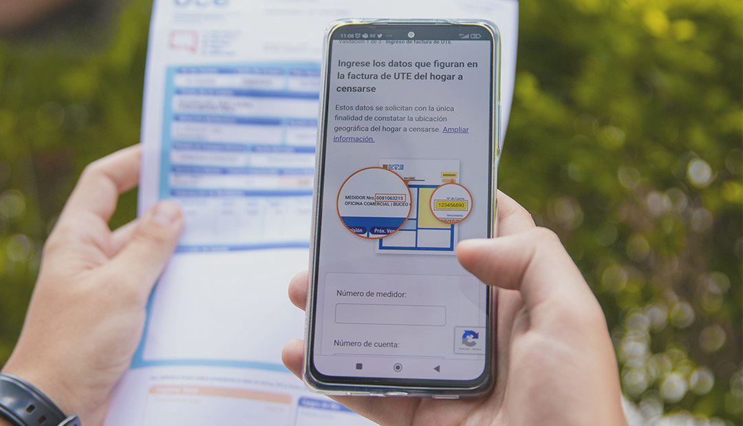 Person holding a smartphone and utility bill, entering data for the census verification form